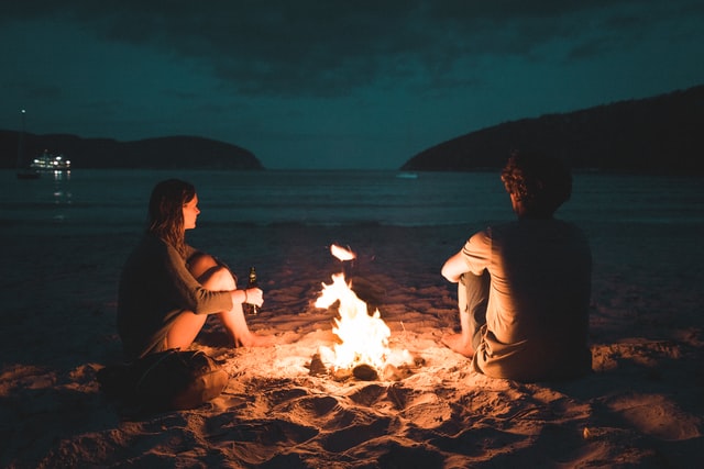 man and woman sitting by fire
